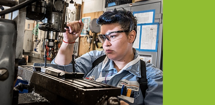 A woman using a drill press.