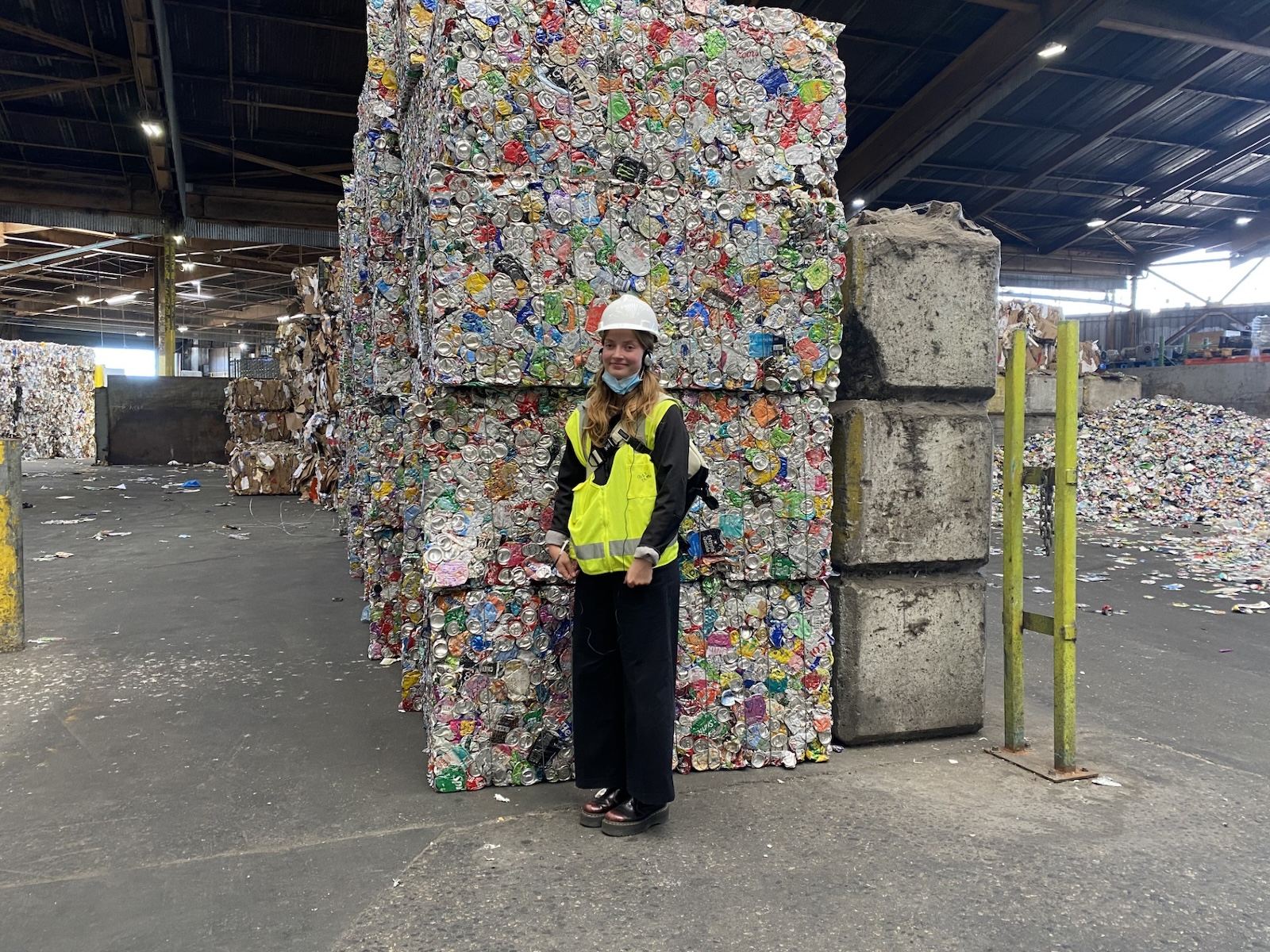 Beatrice stands in front of stacked cubes of compacted recycling