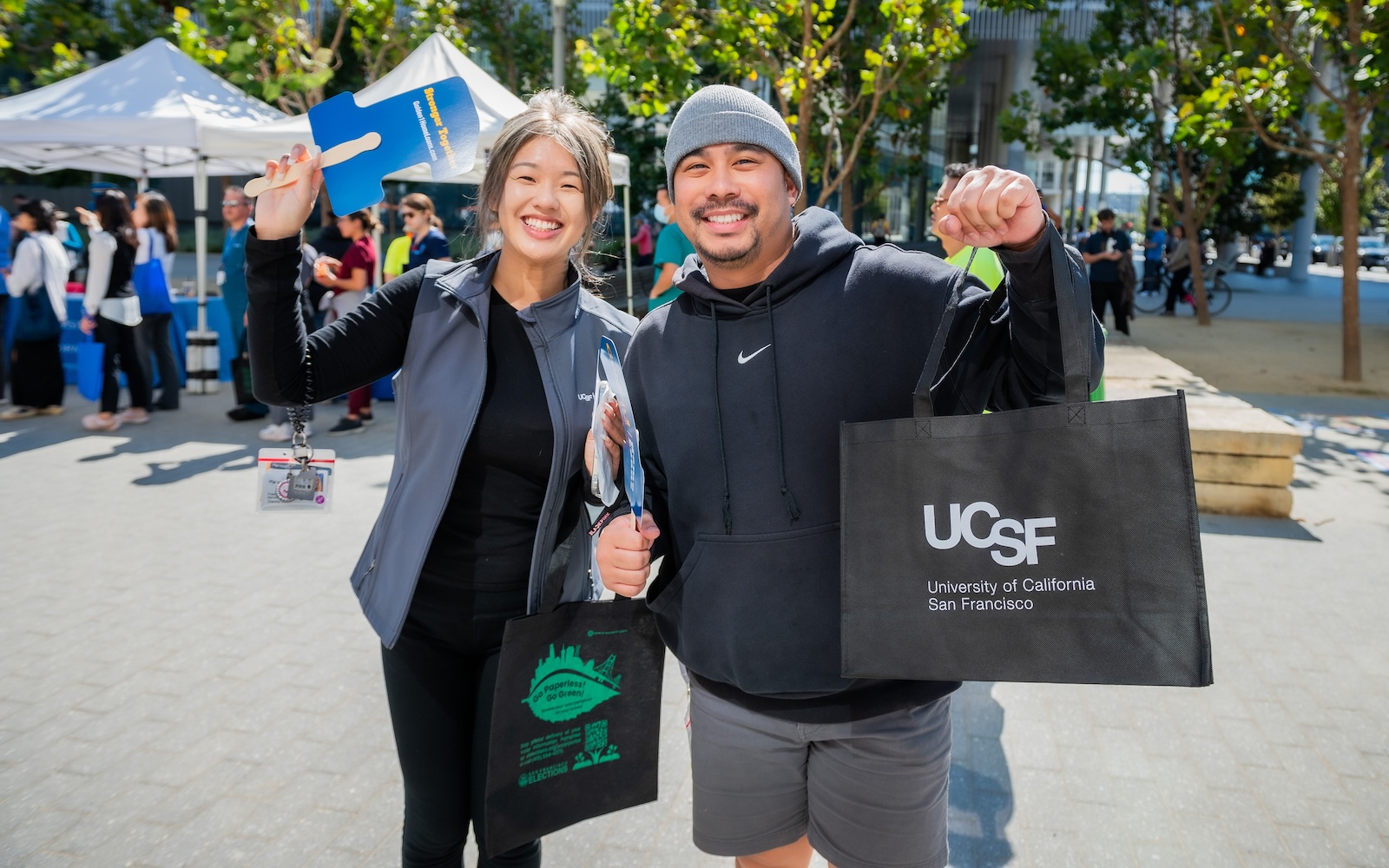 Attendees hold up swag bags from UCSF and discount vendors