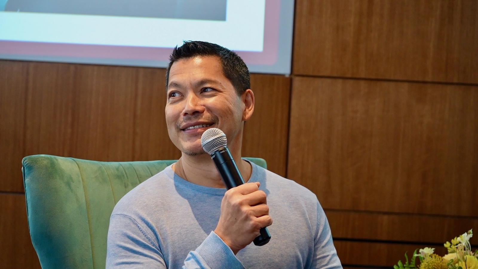 Man speaks into a microphone and smiles at audience