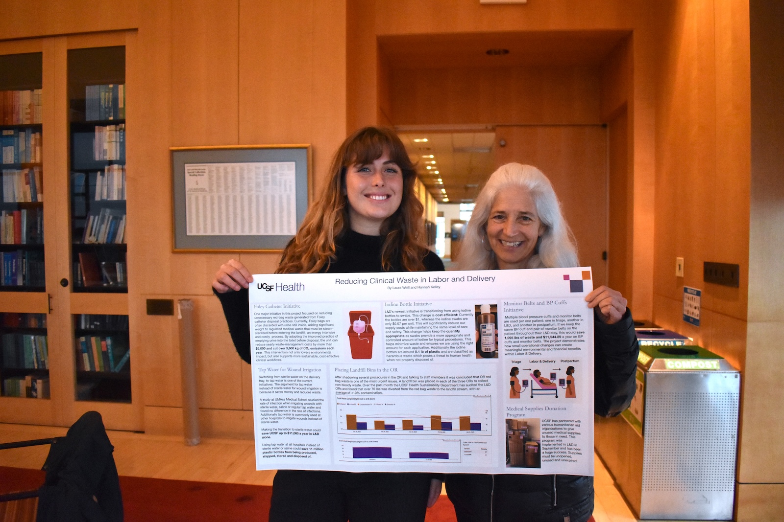Two attendees hold up a research poster