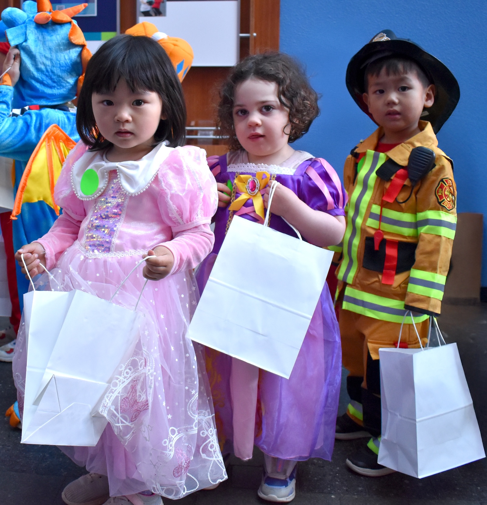 Three children dressed in costumes wait in line to enter FitRec center to trick-or-treat