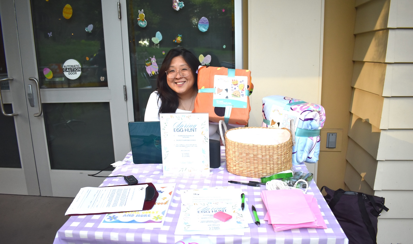 A woman sits at a table holding up a blanket raffle prize