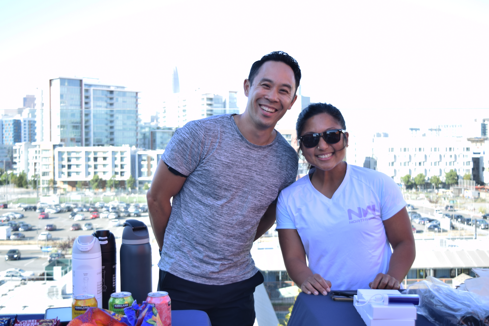 Bakar Operations Manager, Gregory Ong and Lead Operations Clerk, Angel Gapuz pose in front of swag booth, with a view of the skyline in the back gound