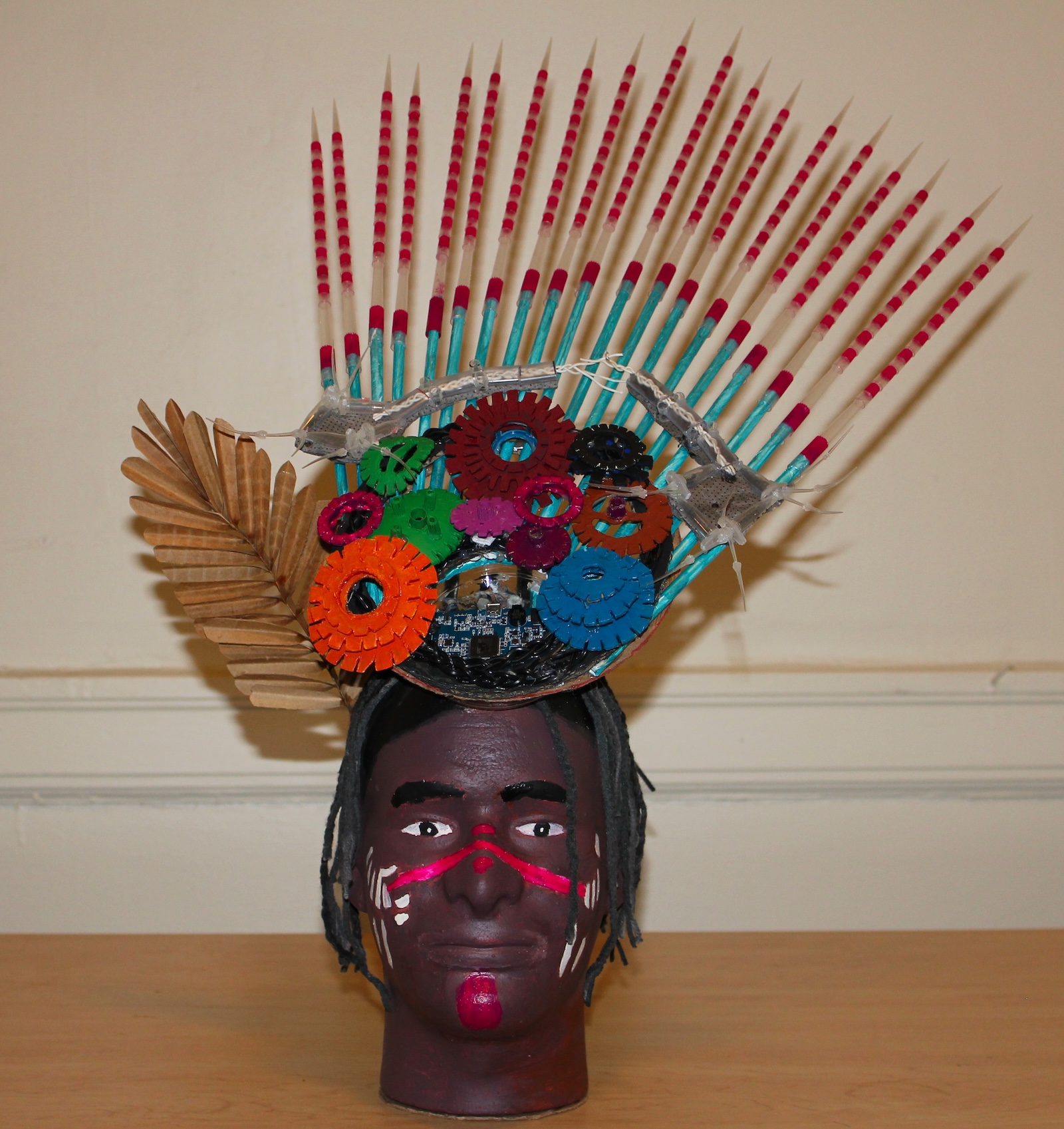 A painted head with headdress made of recycled materials