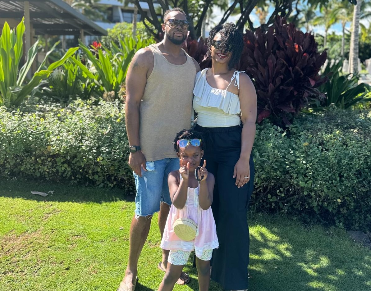 Family poses outside against a lawn and bushes