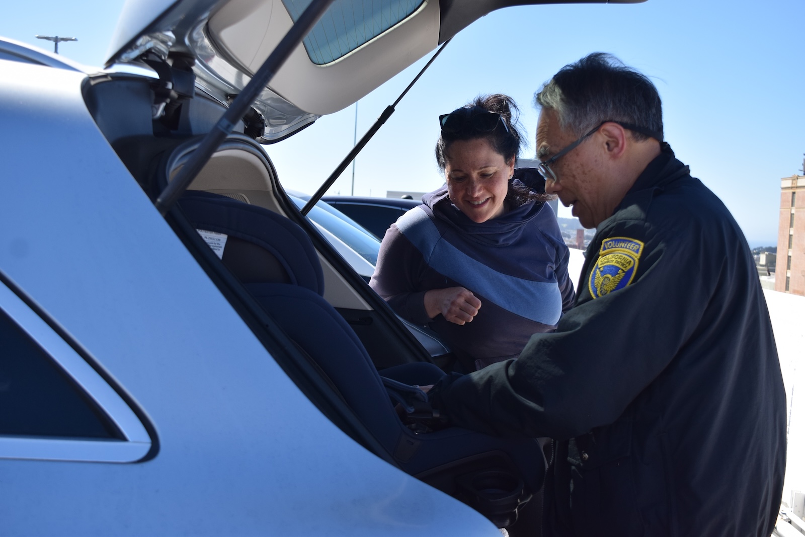 Child Passenger Safety Technician Frank Yee guides parent Rachel White through car seat installation