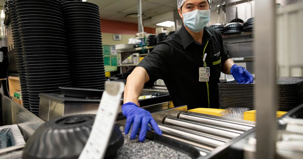 Person in industrial kitchen pushes tray with food