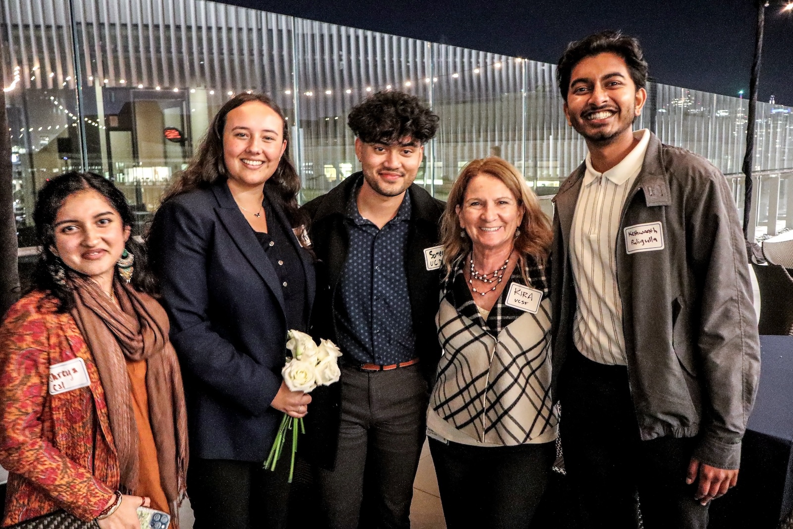 Group poses on rooftop against string lights