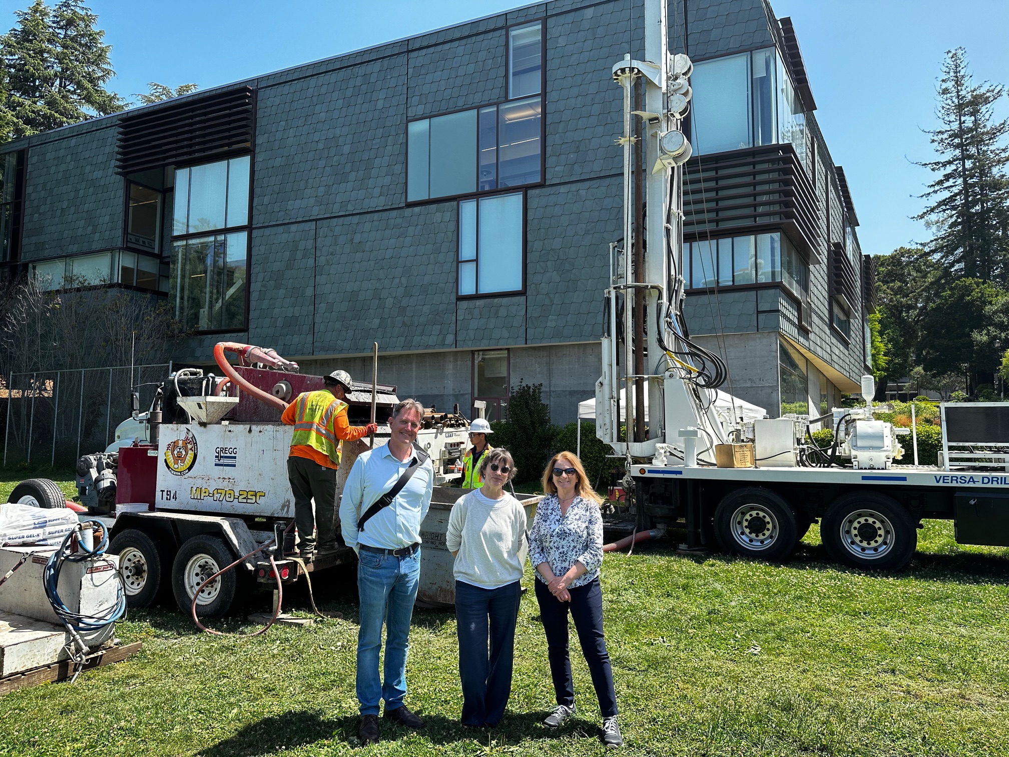 Three people stand in front of boring machines on the UC Berkeley campus
