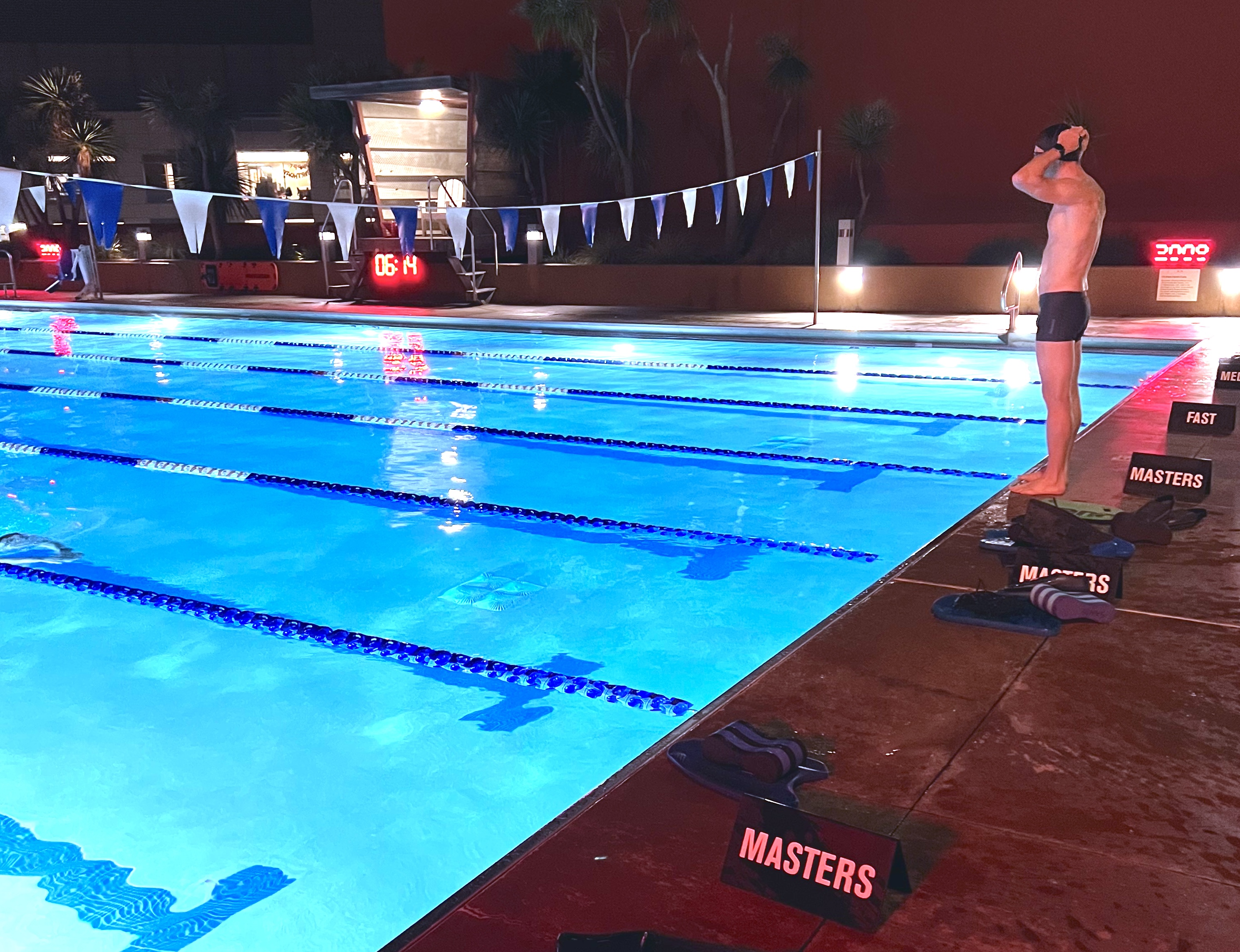 Swimmer adjusts cap while standing at the edge of the pool.