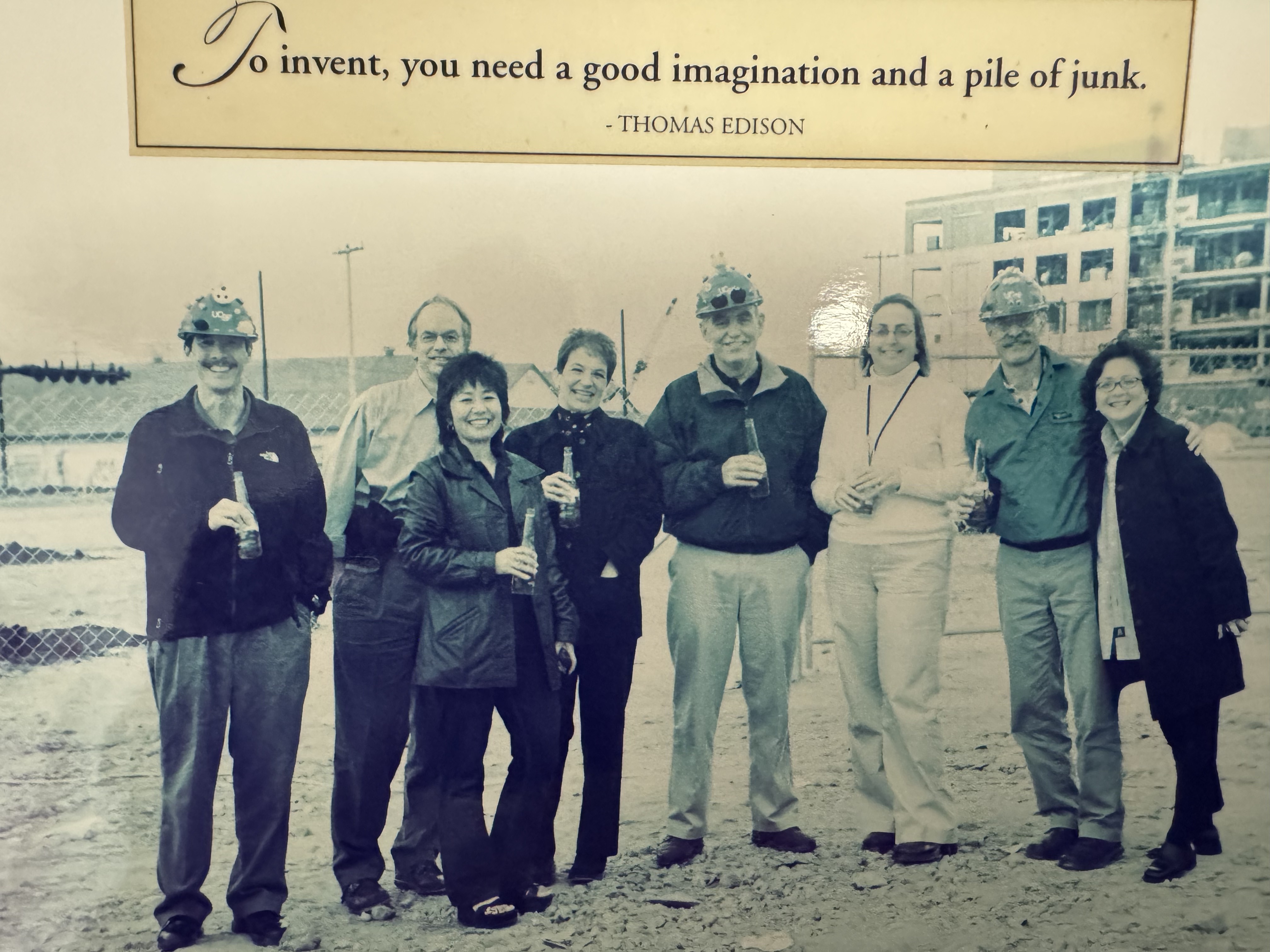 Group of UCSF employees stands against a chain link fence on an empty plot of land