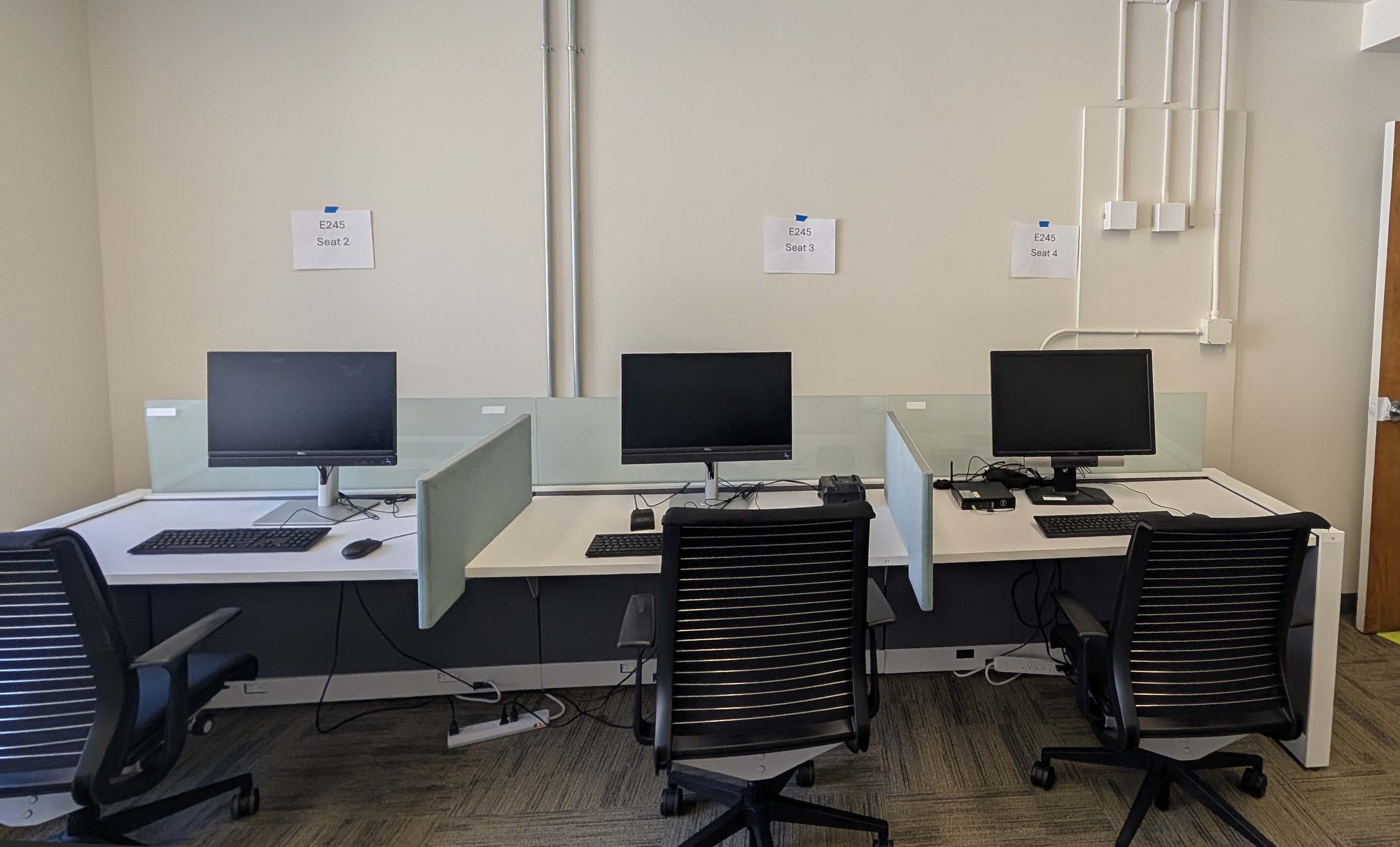 Three computer desktops in a row on a workstatiion