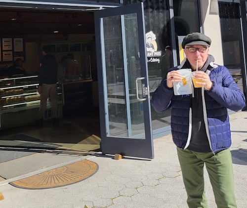 A man holding a NoonBrew tea and a Peasant Pie