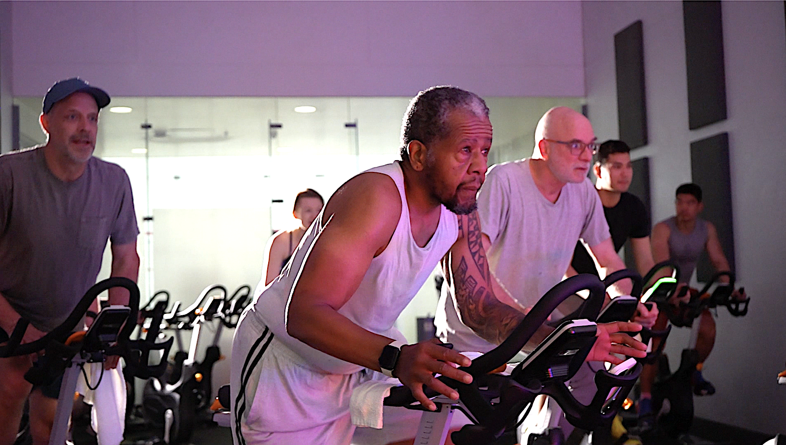 A group of men ride stationary bikes