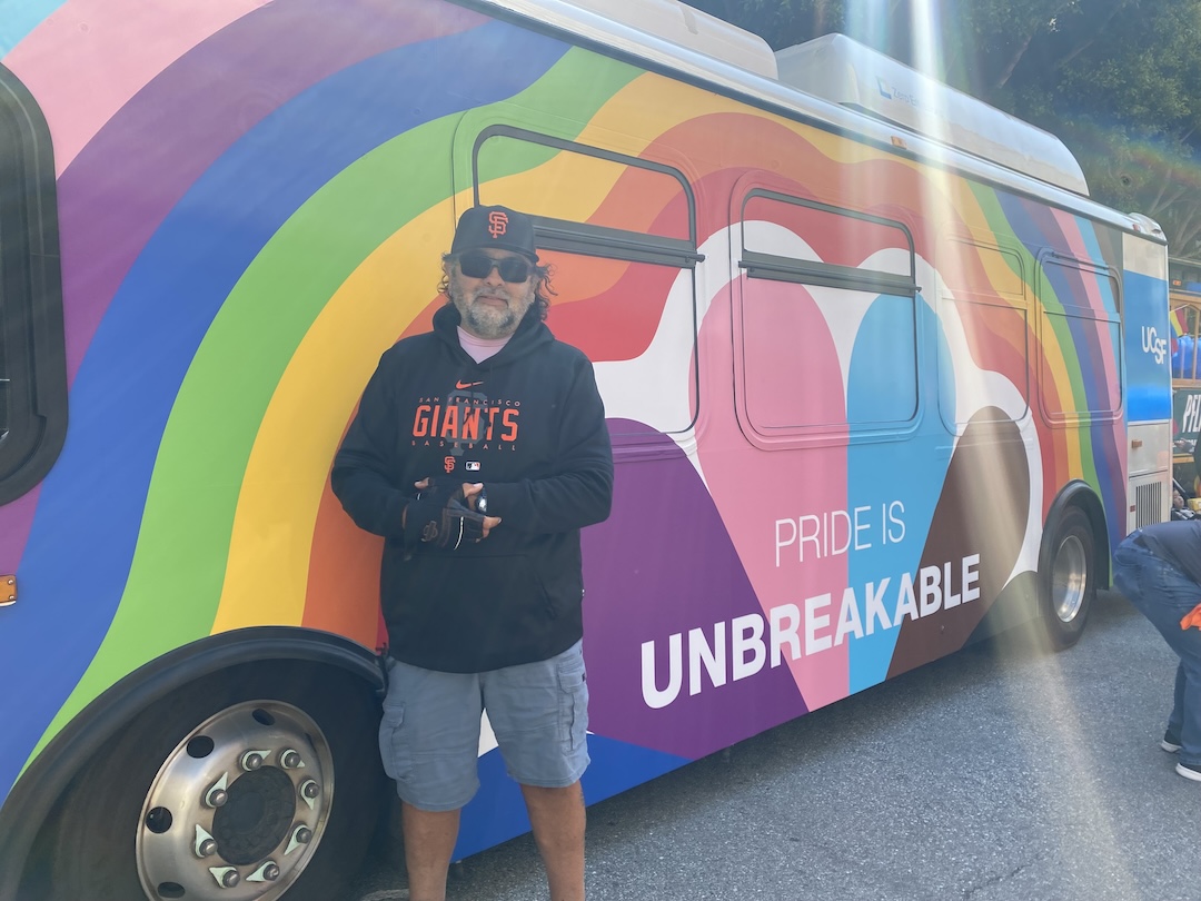 Gus Del Toro stands in front of UCSF Pride bus.