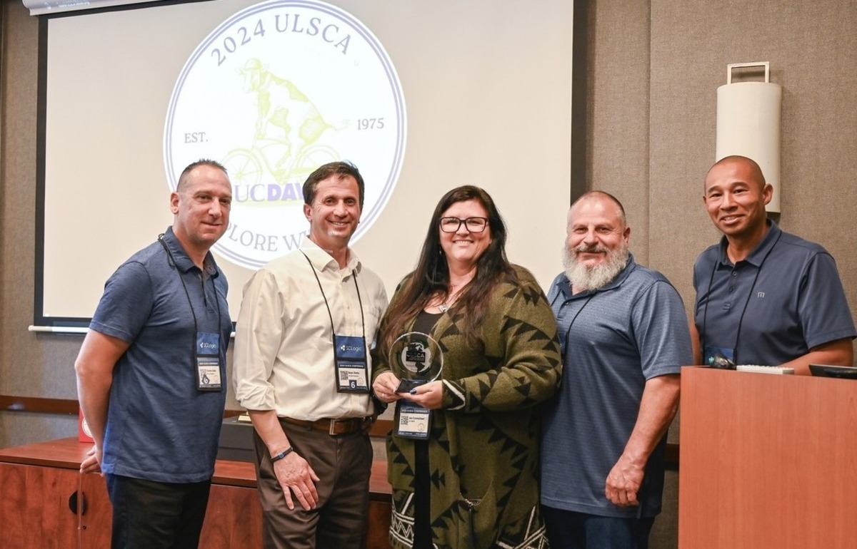 A group of people stands next to a podium in front of a presentation showing the seal of UC Davis