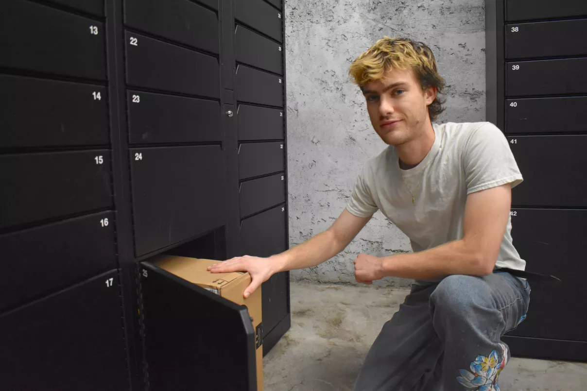 Person kneels in front of a locker while placing a package inside.
